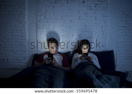 Stock photo: Couple Using Smartphones In Bed At Night