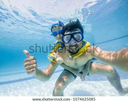 Stok fotoğraf: Dad And Son In Swimming Goggles Have Fun In The Pool