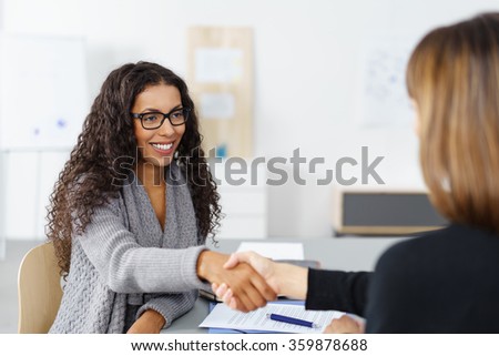 Stockfoto: Two Businesswomen Shaking Hands Over A Desk As They Close A Deal