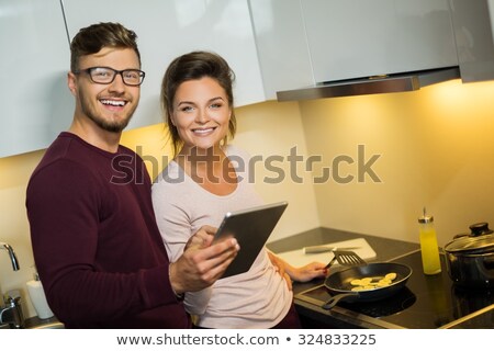 Foto stock: Couple Watching Cookbook In A Kitchen