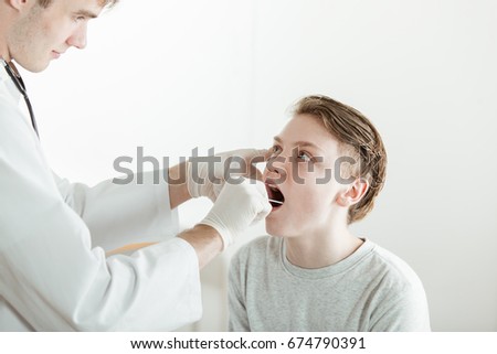 Stok fotoğraf: Sick Child Opening Mouth While Looking At Doctor Examining Her Sore Throat