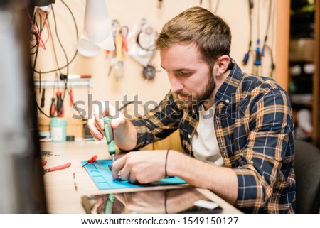 Stok fotoğraf: Repairman Bending Over Broken Gadget And Using Screwdriver To Fix Tiny Parts