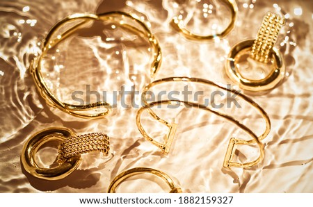 [[stock_photo]]: Golden Bracelets Earrings Rings Jewelery On Gold Water Backgr