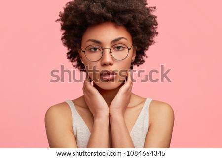 Stok fotoğraf: Headshot Of Pleasant Looking Dark Skinned Woman With Afro Haircut Wears Transparent Glasses And Cas