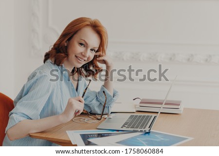 Stock fotó: Satisfied Businesswoman With Foxy Hair Checks Accounting Documentation In Online Database Works On