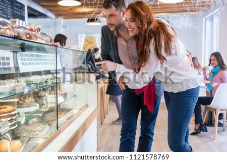 Beautiful Woman Choosing A Delicious Cake While Standing Next To Her B Foto d'archivio © Kzenon