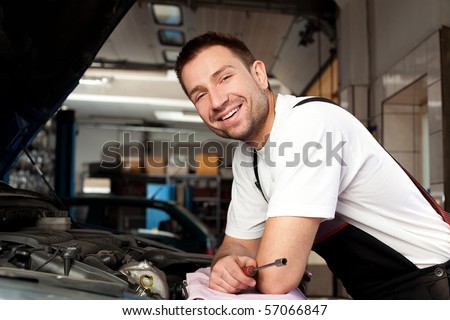 Stockfoto: Handsome Mechanic Based On Car In Auto Repair Shop With Tablet On Hand