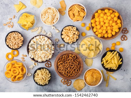 Stockfoto: All Classic Potato Snacks With Peanuts Popcorn And Onion Rings And Salted Pretzels In Bowl Plates O