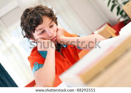 Stok fotoğraf: Teen School Boy Studies Hard Over His Book At Home