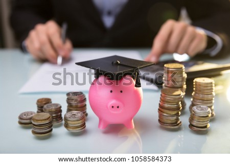 Foto stock: Close Up Of Piggy Bank Wearing Graduation Hat And Stacked Coins