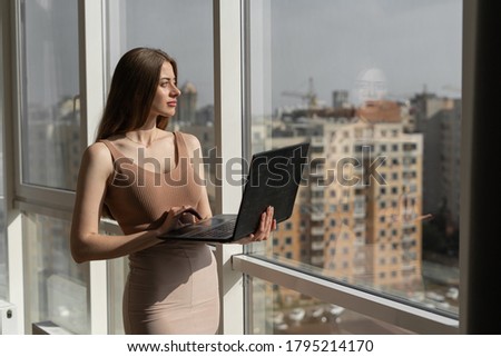 Foto stock: A Young Girl Is Standing Near The Table And Typing Text On The Keyboard Next To The Girl Lie Docume