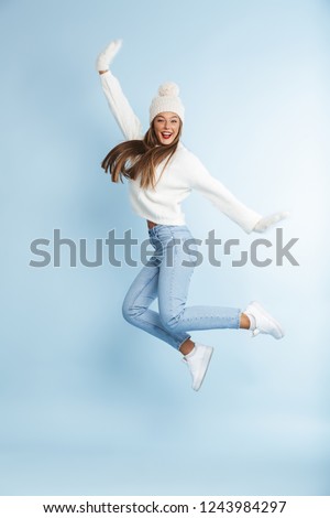 ストックフォト: Cute Young Woman Wearing Winter Hat Jumping Isolated Over Blue Wall Background