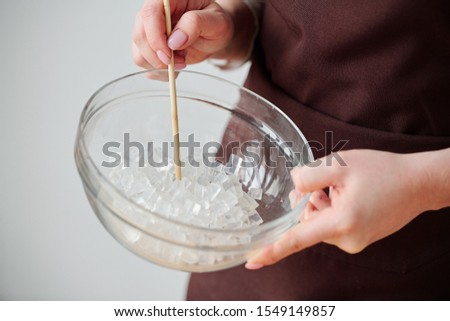 Foto stock: Hands Of Craftswoman Holding Glassware With Cubes Of Cut Transparent Soap Mass