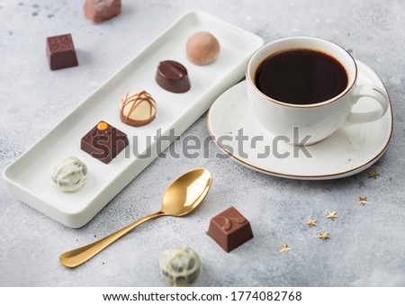 Stockfoto: Luxury Chocolate Candies In White Porcelain Plate With Cup Of Black Coffee And Golden Spoon On Light