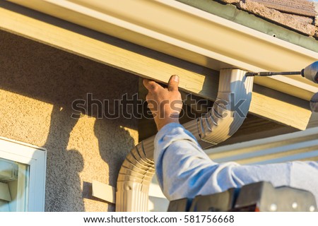 Zdjęcia stock: Worker Attaching Aluminum Rain Gutter And Down Spout To Fascia O