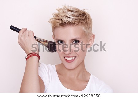 Stockfoto: Portrait Of Attractive Young Adult Woman Applying Blusher Agains