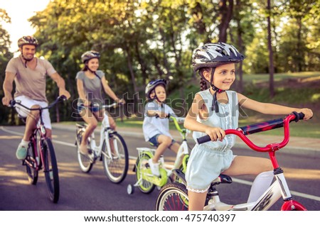 Stockfoto: Happy Family Is Riding Bikes Outdoors And Smiling Mom On A Bike And Son On A Balancebike