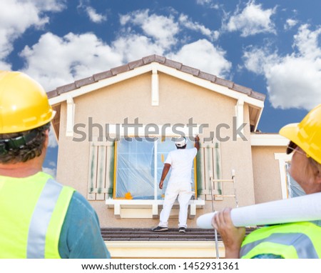 [[stock_photo]]: Male And Female Contractors Overlooking Painter Painting House