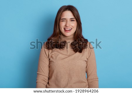 Foto stock: Funny Joyful Brunette Female Shows Tongue Blinks With Eye Makes Grimace Wears Braces Has Long St