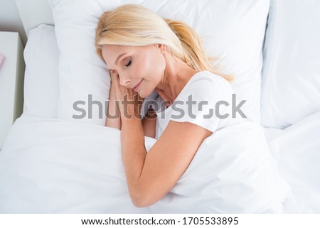 Zdjęcia stock: Pretty Middle Aged Woman Lying On The Bed Wearing White Shirt And Smiling