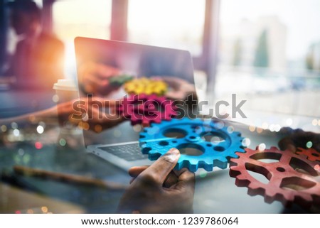 Stockfoto: Business People With Gears In Hand That Exit From A Laptop Concept Of Remote Cooperation And Teamwo