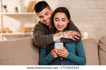 Stock fotó: Young Woman Looking At Mobile Phone Of Her Man Chatting In Jeans Denim Jackets Isolated Over Red Bac