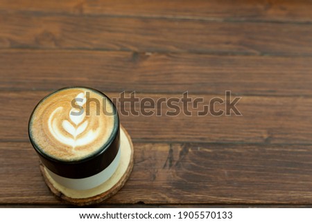 Foto d'archivio: Hot Coffee In Black Cup With Crema And Pattern Beans With Copy Space On Brown Old Wooden Board Back