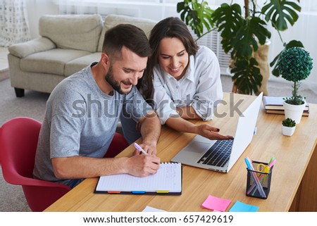 Foto d'archivio: Couple Writing In Notebooks Sitting On Sofa