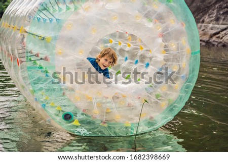 ストックフォト: Cute Little Boy Playing In Zorb A Rolling Plastic Cylinder Ring With A Hole In The Middle Intdoor