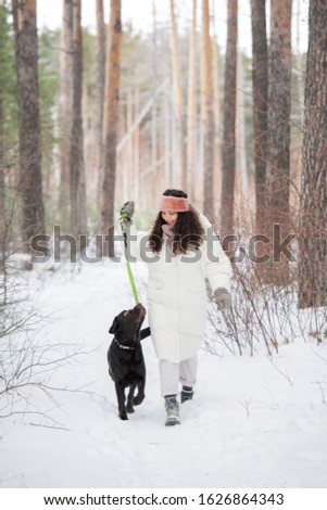 Stockfoto: Happy Young Woman Holding Leash Of Black Retriever While Chilling With Pet