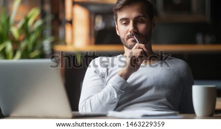 Foto stock: A Young Man Sits At A Table In The Office And Holds A Bank Card And Phone