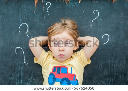 Stock fotó: Top View Of A Little Blond Kid Boy With Question Mark On Blackboard Concept For Confusion Brainsto