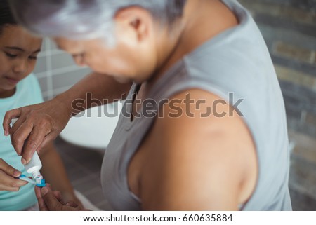 Foto d'archivio: Grandmother Applying Toothpaste On Granddaughters Brush In The Bathroom