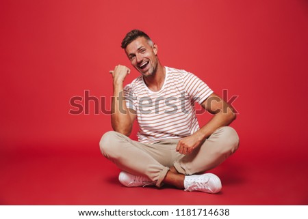 Foto d'archivio: Image Of Positive Man 30s In Striped T Shirt Smiling While Sitt