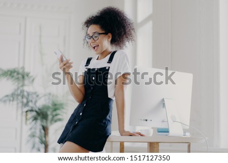 Foto stock: Indoor Shot Of Happily Surprised Young Unexperienced Afro American Woman Wears Spectacles White T S