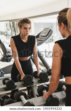 Foto stock: Portrait Of Pretty Young Woman Lifting Dumbbells During Exercisi