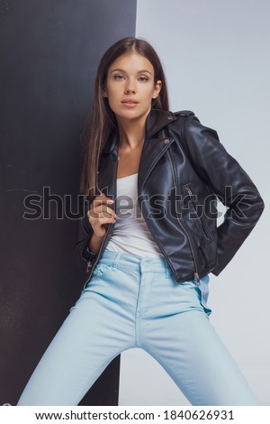 Stock photo: Woman Posing In Studio Arranging Her Leather Jacket While Seated