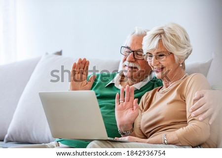 Foto d'archivio: Side View Of Active Senior Man Using Laptop While Senior Couple Using Digital Tablet At Nursing Home