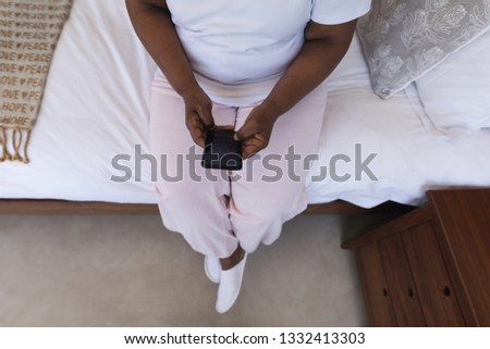 Foto stock: Low Section Of Senior African American Woman Using Mobile Phone In Bedroom At Home