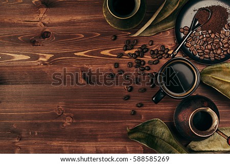 Stock photo: Hot Coffee In Black Cup With Beans Dry Leaves And Turkish Pot Cezve With Copy Space On Brown Old Wo