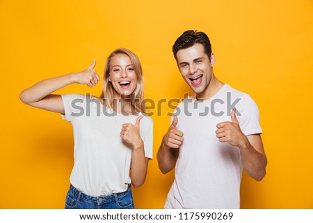 Stock fotó: Excited Young Loving Couple Standing Isolated Over Yellow Wall Background Pointing To Each Other