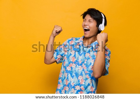 Stok fotoğraf: Excited Young Asian Man Standing Isolated Over Yellow Background Holding Pizza Drinking Beer
