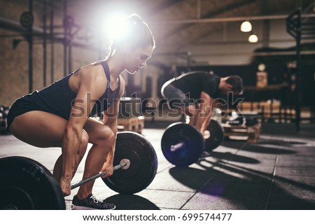 Foto d'archivio: Athletic Man And Woman With Barbell Doing Exercises In The Gym