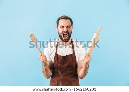 Zdjęcia stock: Emotional Screaming Young Man Chef Indoors Isolated Over White Wall Background Holding Knife Showing