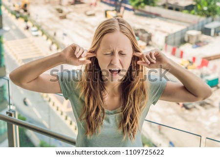 Stock photo: A Young Woman By The Window Annoyed By The Building Works Outside Noise Concept