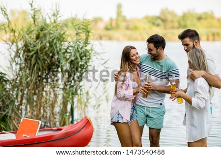 Foto stock: Group Of Friends With Cider Bottles Standing By The Boat Near Th