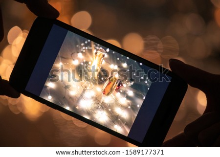 ストックフォト: Human Hands Holding Smartphone With Image Of Two Flutes Of Champagne On Table