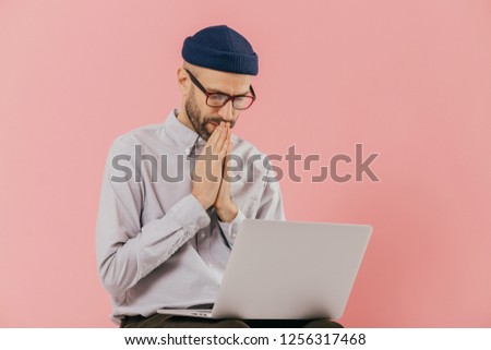 Stock foto: Professional Male Programmer Keeps Hans In Praying Gesture Looks At Screen Of Laptop Computer Beli