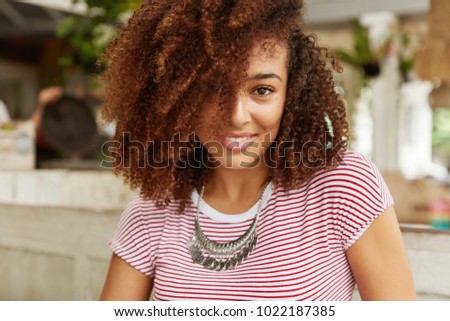Stockfoto: Headshot Of Cute Lovely Woman Has Broad Smile Dark Hair Keeps Hand On Ear Shows White Teeth With