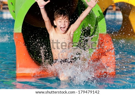 Foto d'archivio: Happy Boy On Water Slide In A Swimming Pool Having Fun During Summer Vacation In A Beautiful Tropica